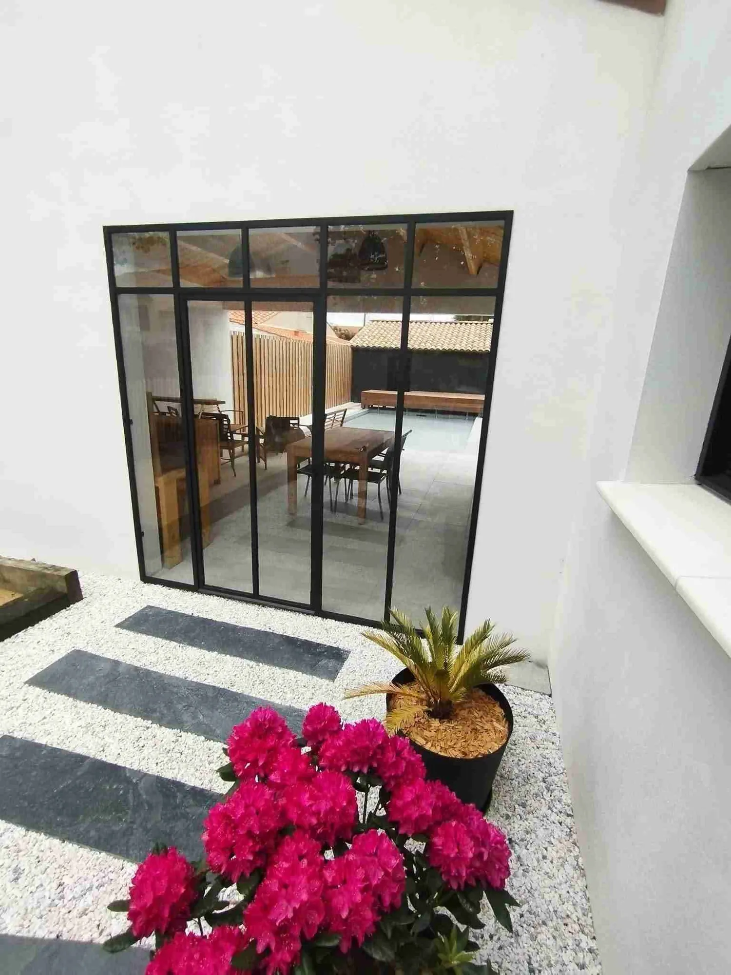 Verrière acier noir donnant sur une terrasse avec piscine