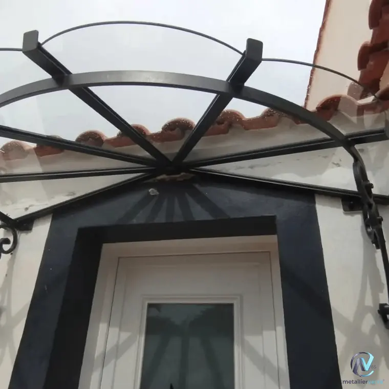 Marquise cintrée en fer forgé au-dessus d'une porte d'entrée