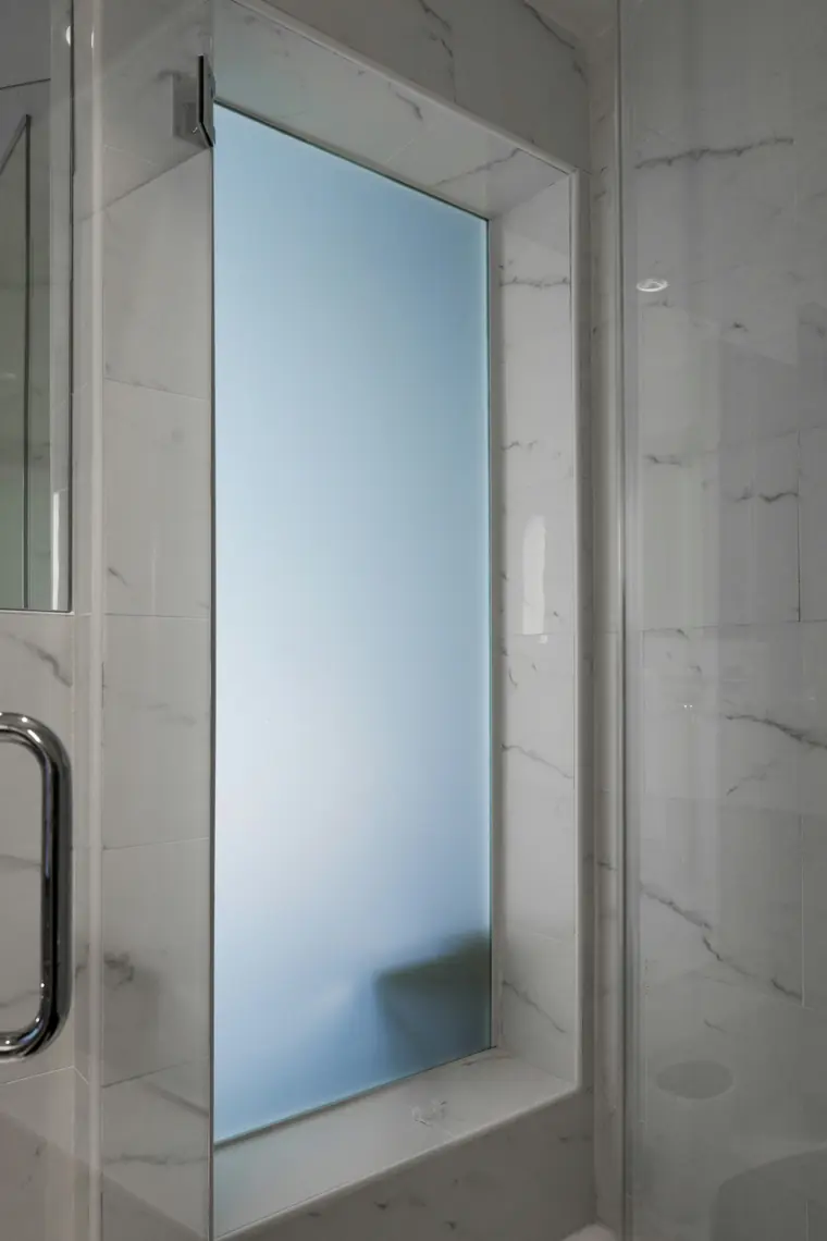 Châssis en verre dépoli dans une douche carrelée de marbre